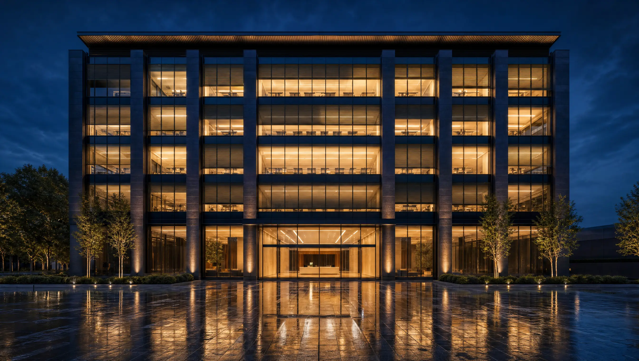 A contemporary corporate building at dusk, every floor warm-lit, reflected in the plaza below